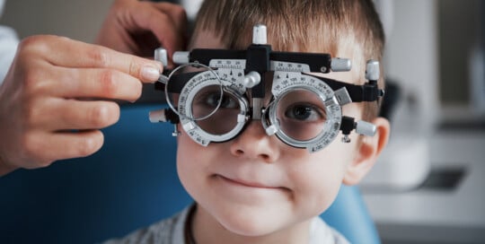 Tuning the intrument. Little boy with phoropter - Our Services